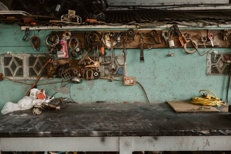 Oude werkbank met gereedschap tegen een groene wand