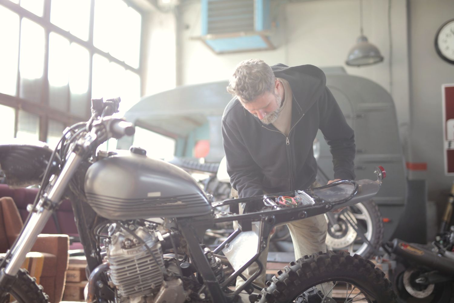 Monteur buigt zich over het motorblok van een klassieke motorfiets