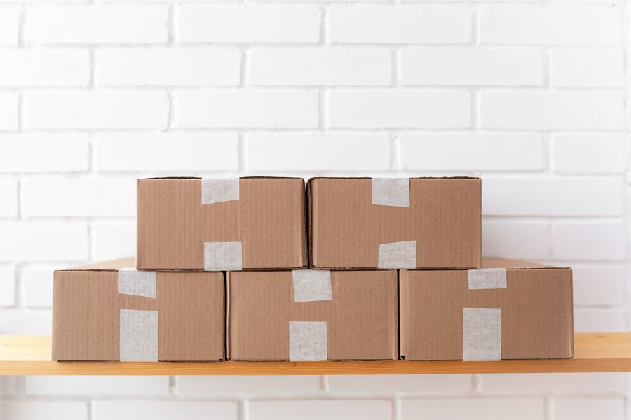 Kartonnen dozen op een houten schap tegen een witte muur